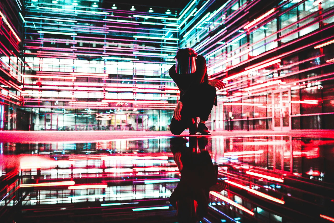 a man kneeling in a room full of lights. Photo by Drew Dizzy Graham on Unsplash