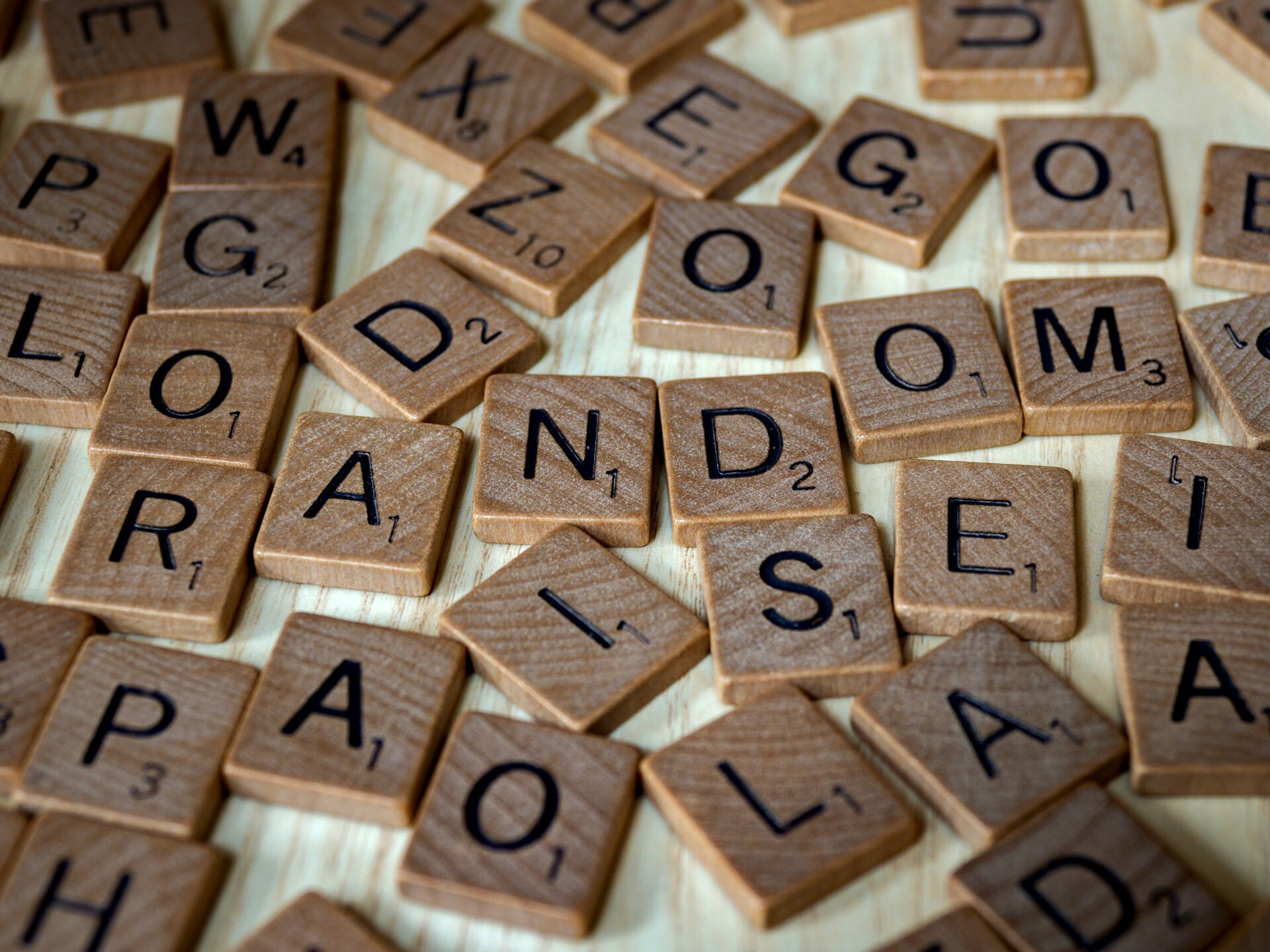 A scattered assortment of wooden Scrabble tiles shaping the word 