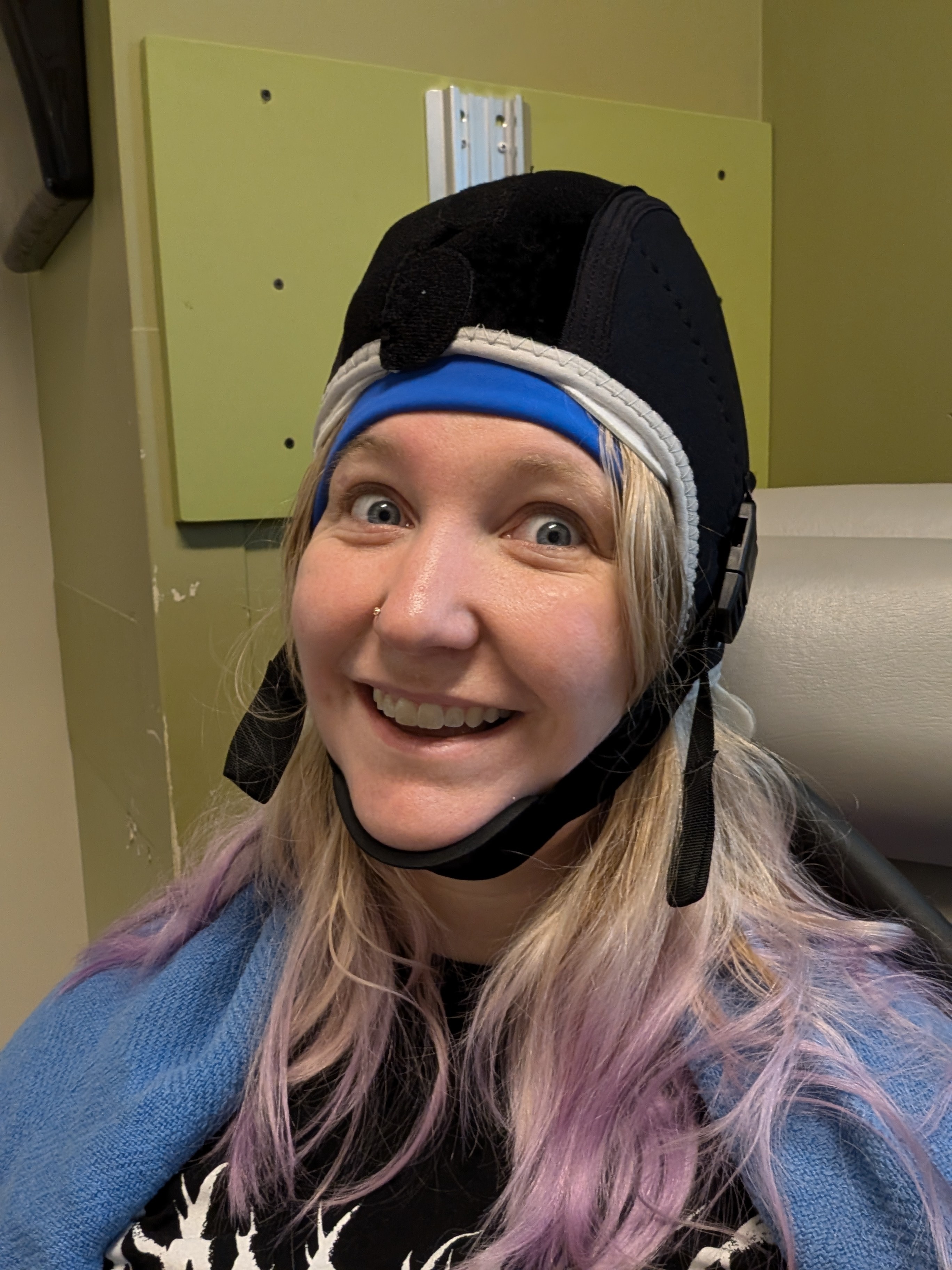 Abbey in the infusion chair, wrapped in blankets in a hat that makes her look like an old timey fighter pilot.