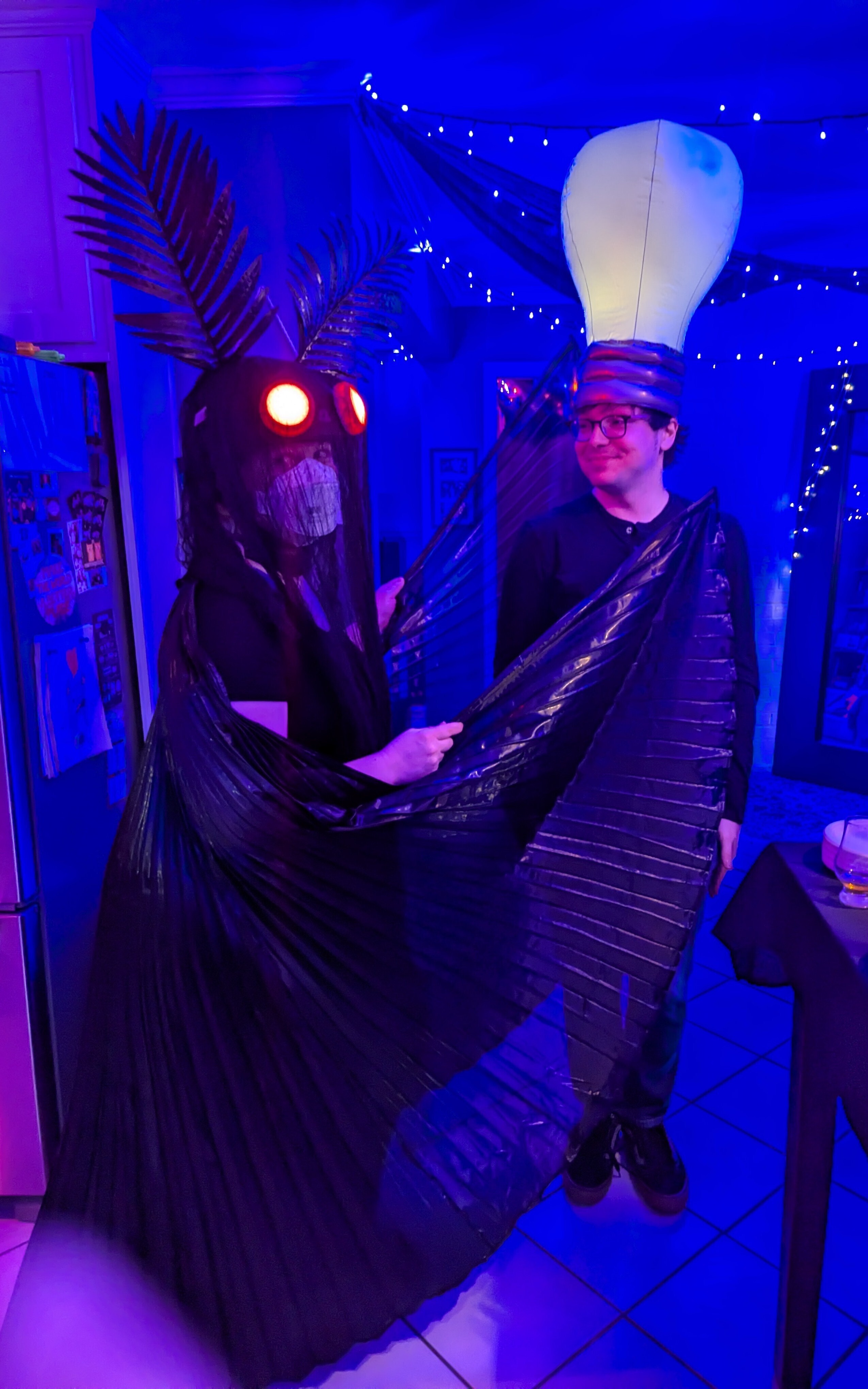 Abbey dressed as Mothman and her husband wearing a lightbulb hat